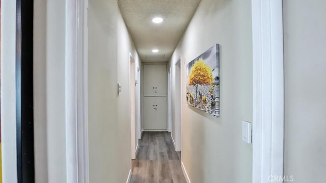 hallway with light hardwood / wood-style floors and a textured ceiling