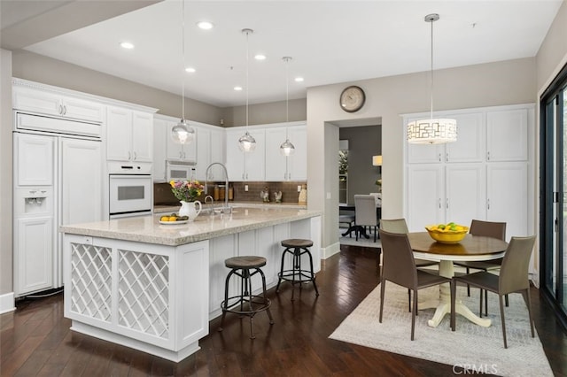 kitchen with hanging light fixtures, white cabinetry, sink, and white appliances