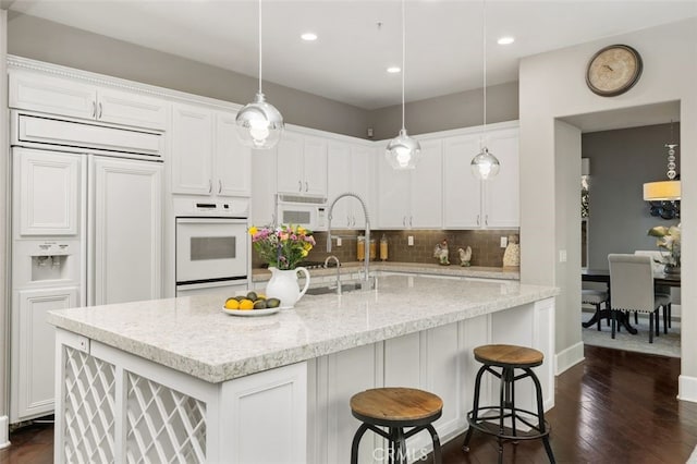 kitchen with white cabinetry, light stone counters, and white appliances