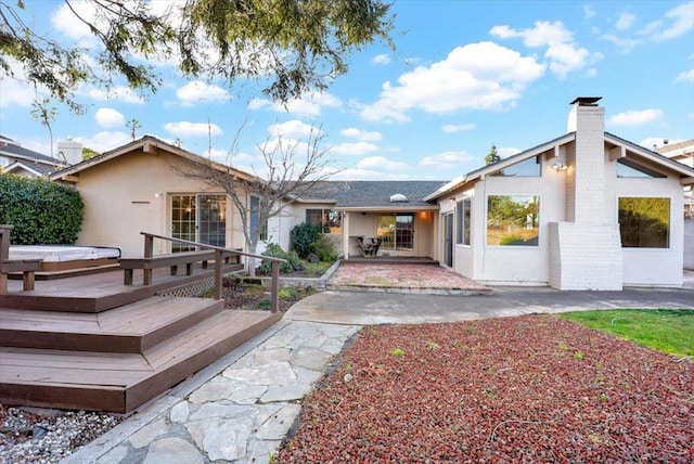 view of front of home featuring a hot tub, a patio, and a wooden deck