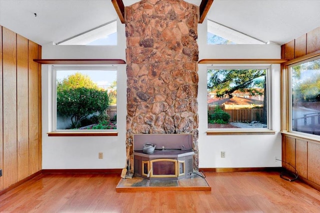 interior space with plenty of natural light, lofted ceiling with beams, and a wood stove