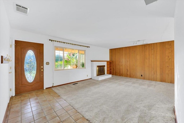 interior space featuring a brick fireplace, light carpet, track lighting, and wooden walls