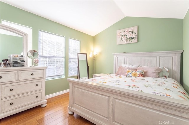 bedroom featuring lofted ceiling, baseboards, and light wood-style floors