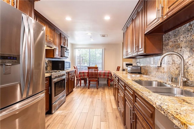 kitchen featuring tasteful backsplash, visible vents, stainless steel appliances, light wood-style floors, and a sink