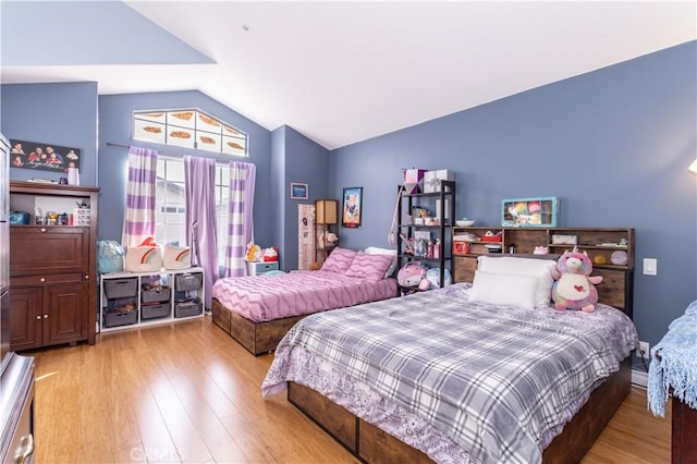 bedroom with lofted ceiling and light wood finished floors