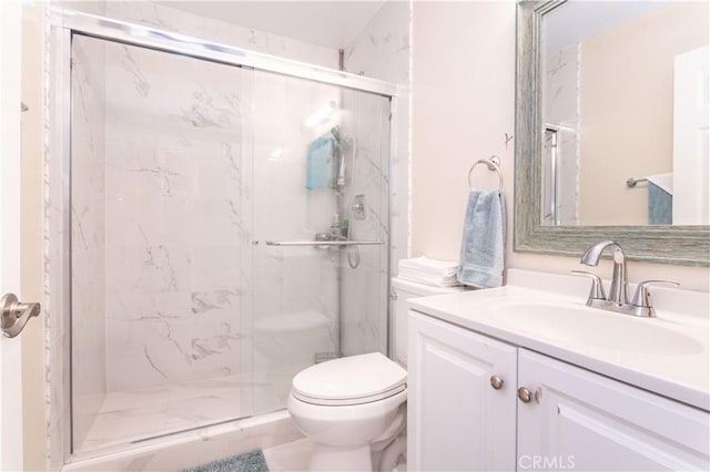 bathroom with toilet, a marble finish shower, and vanity