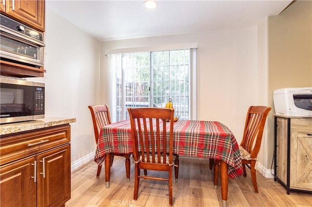 dining area featuring light wood finished floors and baseboards