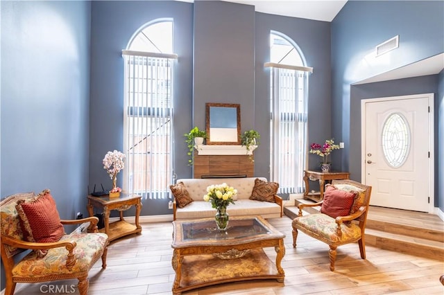 sitting room featuring plenty of natural light, a high ceiling, visible vents, and wood finished floors