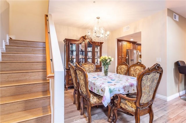 dining area featuring stairs, a chandelier, visible vents, and light wood-style floors