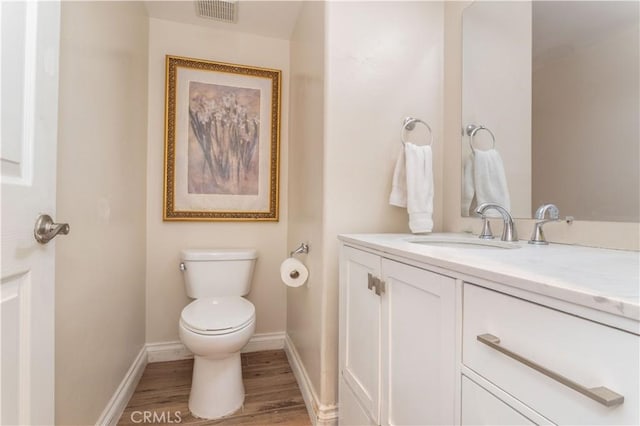 bathroom with baseboards, visible vents, toilet, wood finished floors, and vanity