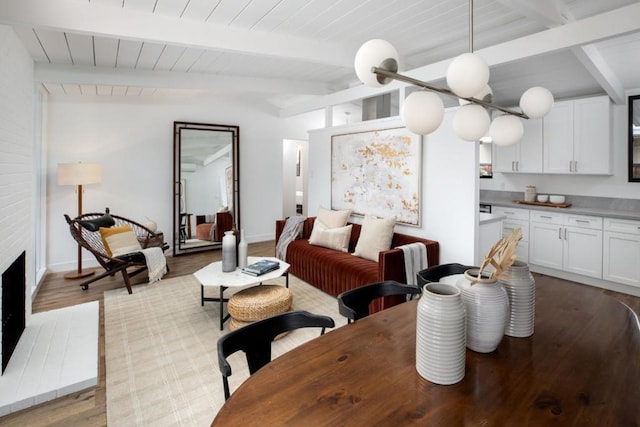 dining area featuring wood ceiling, a fireplace, light hardwood / wood-style flooring, and vaulted ceiling with beams