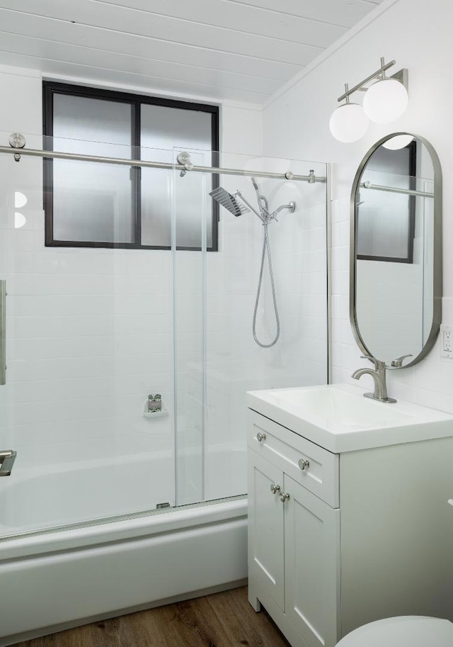 bathroom with wood-type flooring, ornamental molding, vanity, and shower / bath combination with glass door