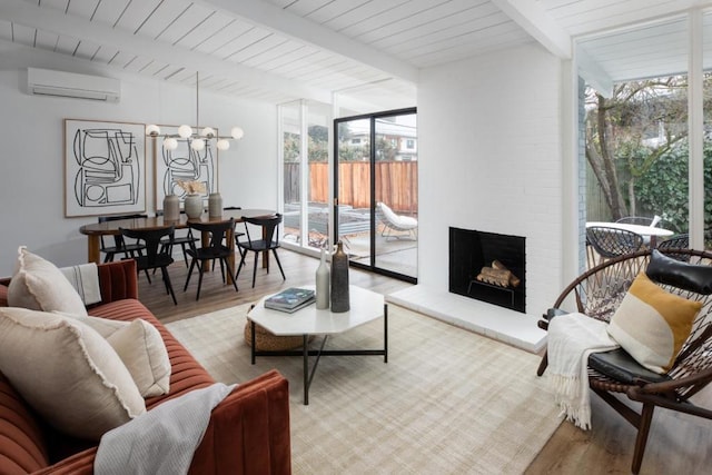 living room featuring a fireplace, beamed ceiling, a wall mounted AC, expansive windows, and light hardwood / wood-style flooring