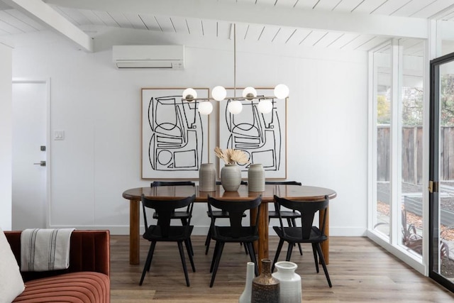 dining area featuring a notable chandelier, lofted ceiling with beams, an AC wall unit, and light wood-type flooring