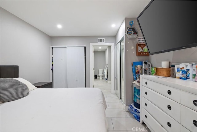 bedroom with light tile patterned floors, connected bathroom, and multiple closets