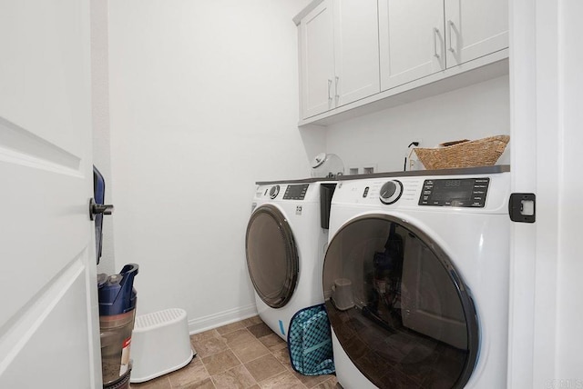 clothes washing area with cabinets and washing machine and clothes dryer