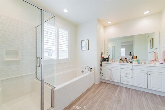 bathroom featuring vanity, wood-type flooring, and plus walk in shower