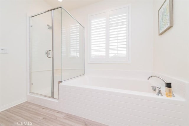 bathroom with shower with separate bathtub and wood-type flooring