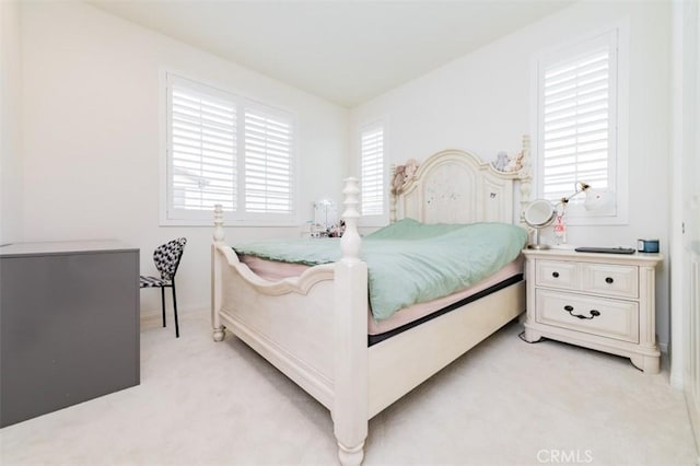 bedroom featuring light carpet and multiple windows