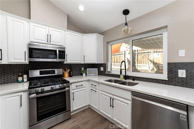 kitchen with pendant lighting, appliances with stainless steel finishes, sink, and white cabinets