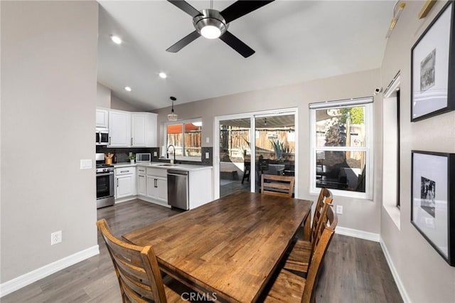 dining space featuring vaulted ceiling, sink, dark wood-type flooring, and a wealth of natural light