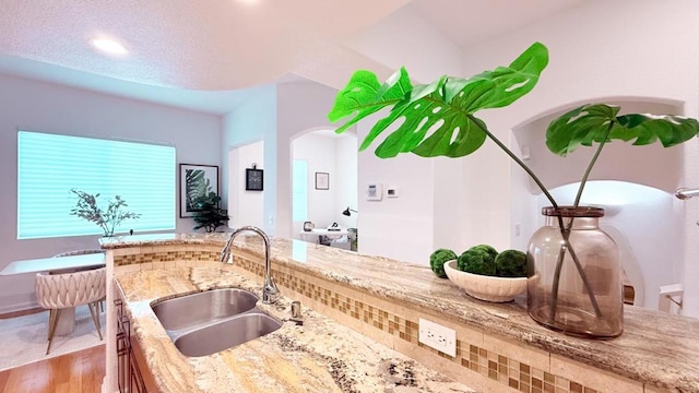 kitchen with light stone counters, sink, and wood-type flooring