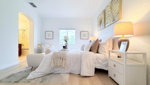 bedroom with light wood-type flooring and ensuite bath