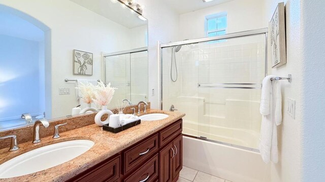 bathroom with tile patterned floors, shower / bath combination with glass door, and vanity