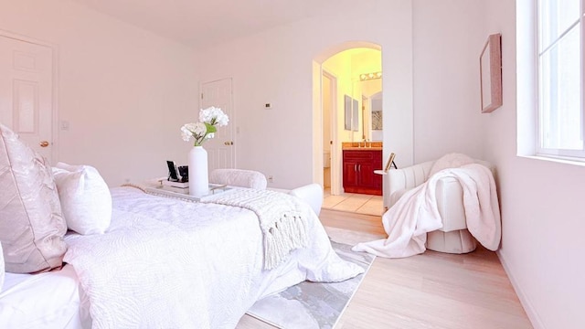 bedroom with sink, ensuite bath, and light hardwood / wood-style flooring