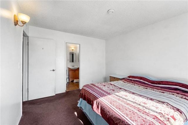 carpeted bedroom with connected bathroom and a textured ceiling