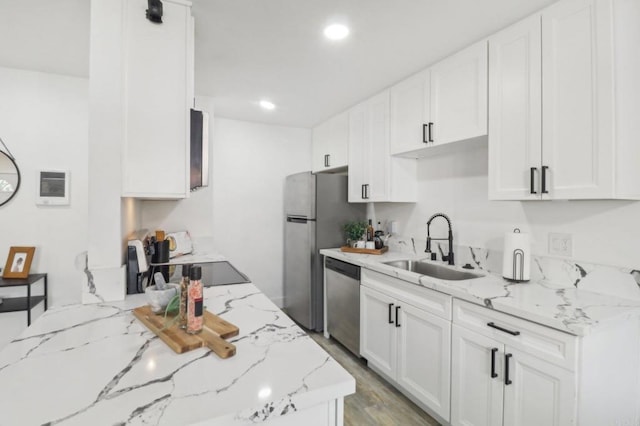 kitchen featuring light stone counters, white cabinetry, stainless steel appliances, and sink