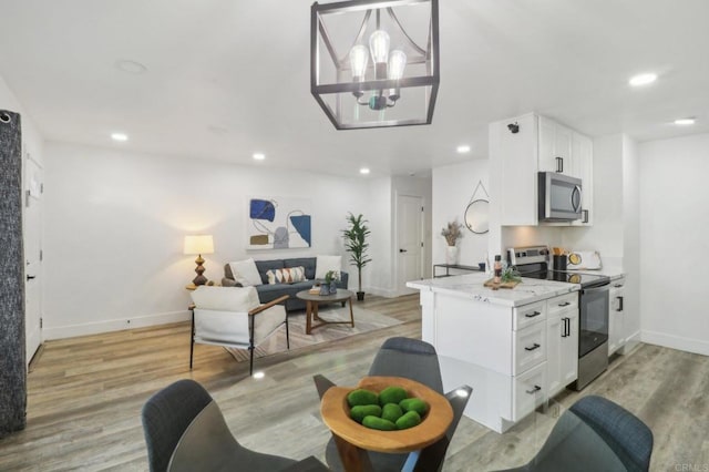 kitchen featuring light stone counters, light wood-type flooring, white cabinets, and appliances with stainless steel finishes