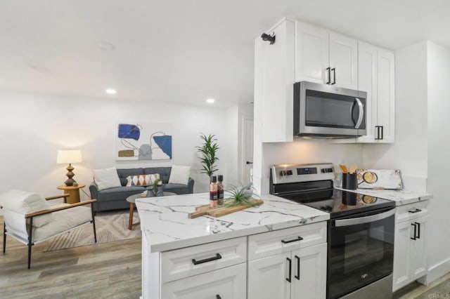 kitchen featuring light stone counters, appliances with stainless steel finishes, light wood-type flooring, and white cabinets