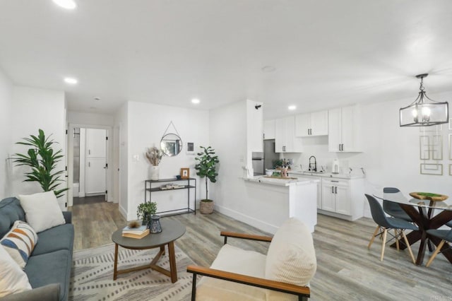 living room featuring an inviting chandelier, light hardwood / wood-style floors, and sink