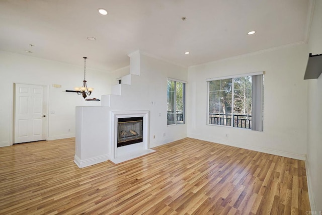 unfurnished living room with crown molding, a notable chandelier, and light hardwood / wood-style floors