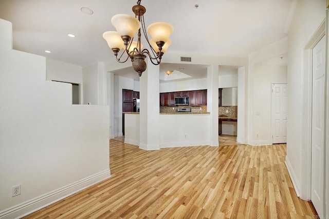 unfurnished living room featuring a notable chandelier and light wood-type flooring