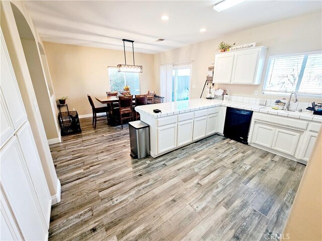 kitchen with white cabinets, decorative light fixtures, kitchen peninsula, and dishwasher