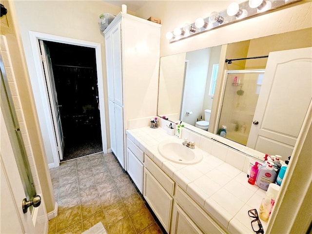 bathroom with vanity, toilet, and a shower with door