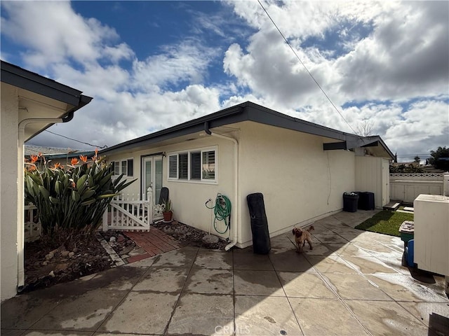view of property exterior with a patio area, stucco siding, and fence