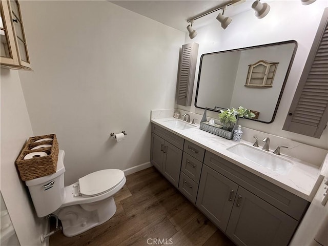 bathroom with double vanity, a sink, toilet, and wood finished floors