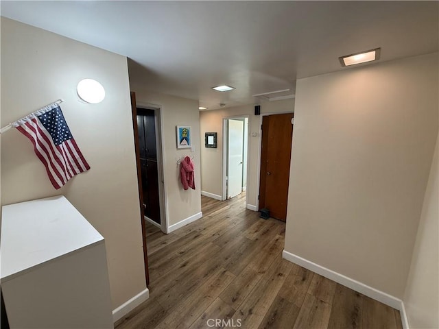 corridor featuring baseboards and wood finished floors