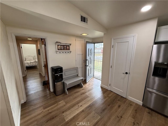 corridor with hardwood / wood-style flooring and lofted ceiling