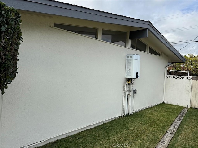 view of side of home with a yard, stucco siding, and fence