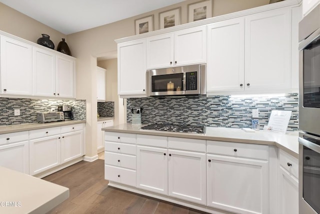 kitchen with stainless steel appliances, dark hardwood / wood-style flooring, decorative backsplash, and white cabinets