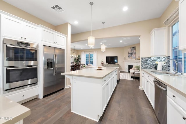 kitchen featuring pendant lighting, sink, stainless steel appliances, tasteful backsplash, and white cabinets