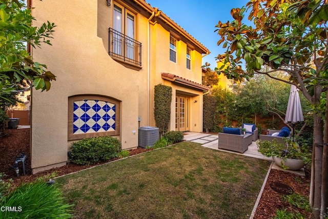 rear view of house with an outdoor living space, cooling unit, a patio area, and a lawn