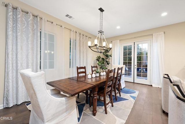 dining area featuring wood-type flooring, an inviting chandelier, and french doors