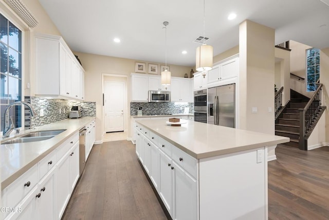 kitchen featuring white cabinetry, appliances with stainless steel finishes, a center island, and hanging light fixtures