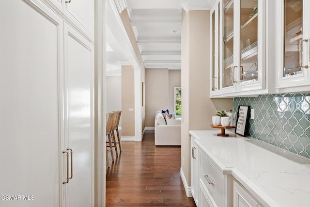 bar featuring tasteful backsplash, white cabinetry, crown molding, light stone countertops, and dark wood-type flooring