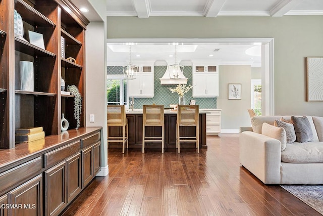 living room featuring ornamental molding, dark hardwood / wood-style flooring, sink, and beam ceiling